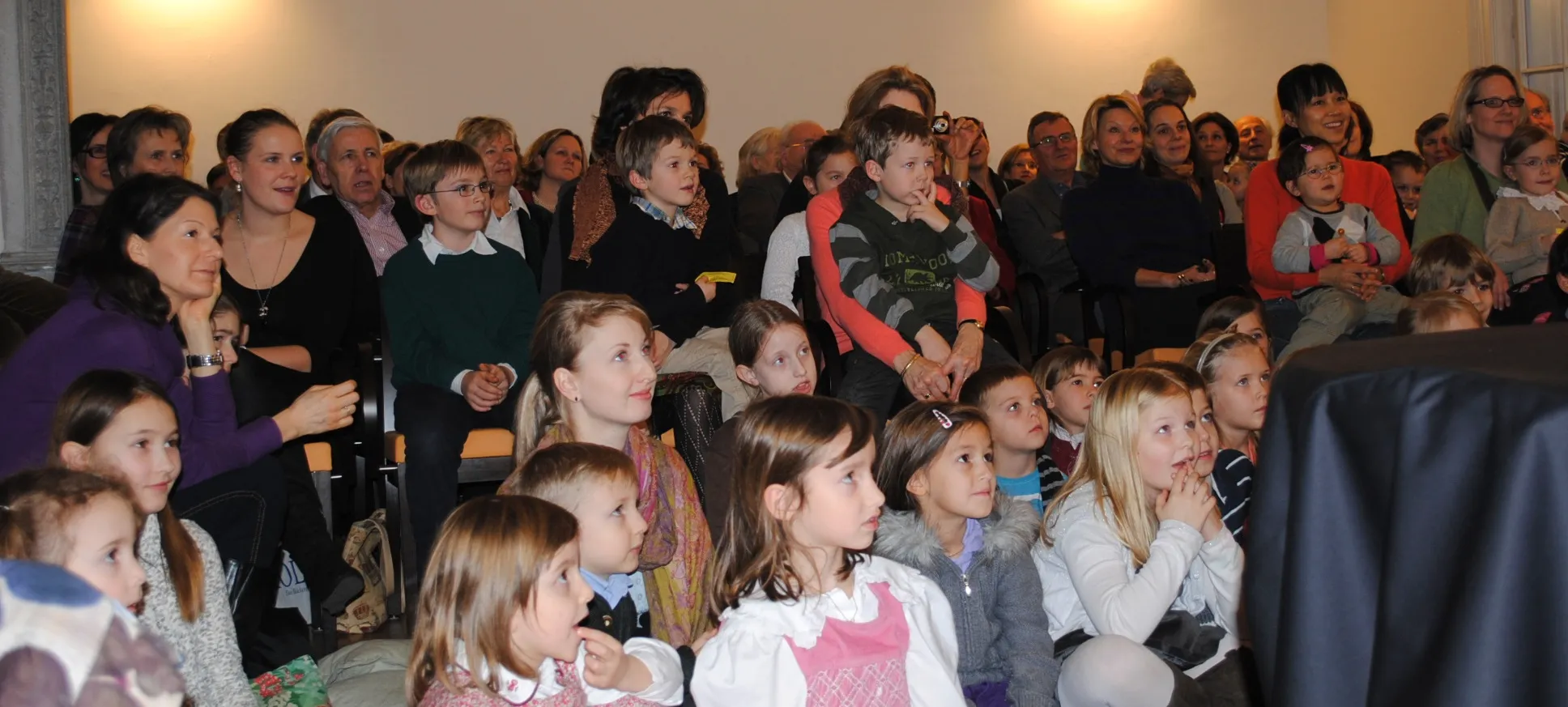 Kinder und Erwachsene verfolgen gespannt eine Aufführung